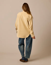 Women's oversized corduroy shacket in cream, back view, paired with wide-leg jeans