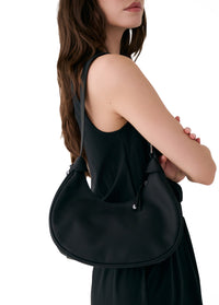 Black hobo bag worn on shoulder with curved silhouette and drawstring closure