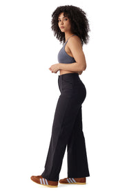 Women's high-waisted wide-leg black travel trousers, side view on model