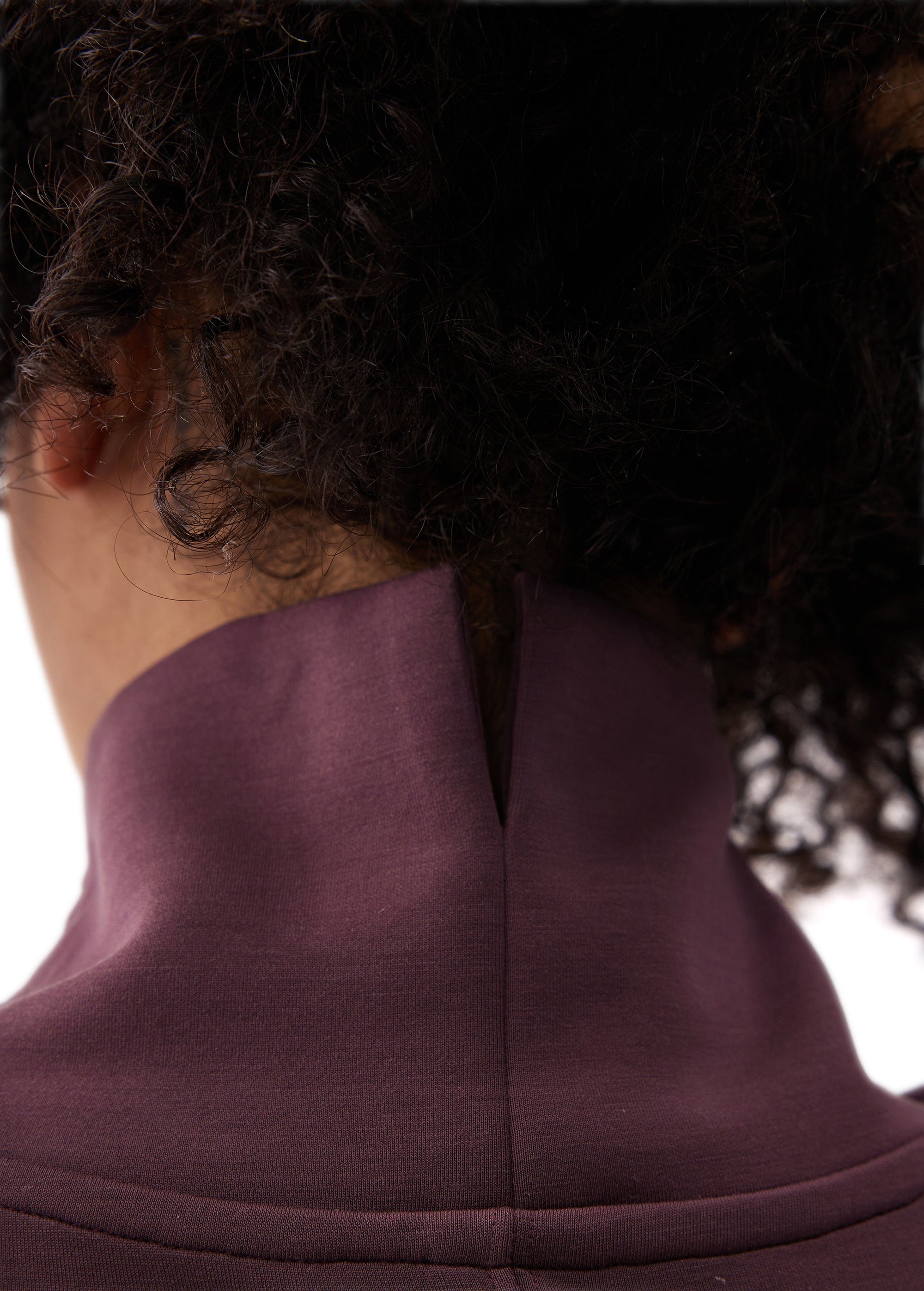 Back neck detail of a long-sleeve tunic with mock turtleneck collar and center seam