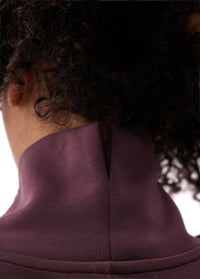 Back neck detail of a long-sleeve tunic with mock turtleneck collar and center seam