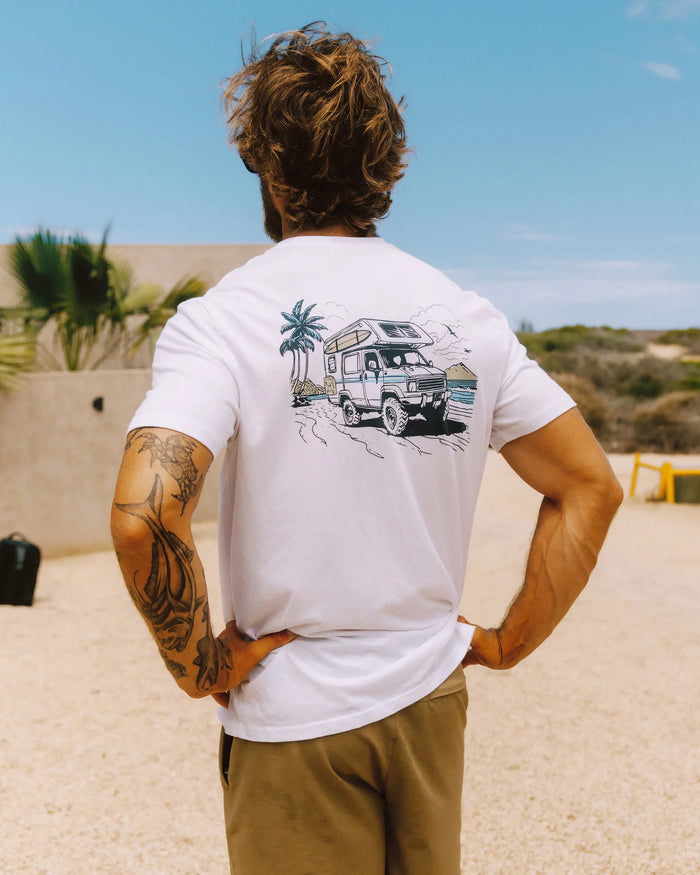 White t-shirt with adventure vehicle graphic on back, worn by tattooed person outdoors