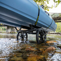 Blue kayak cart with airless wheels positioned in shallow water near bridge