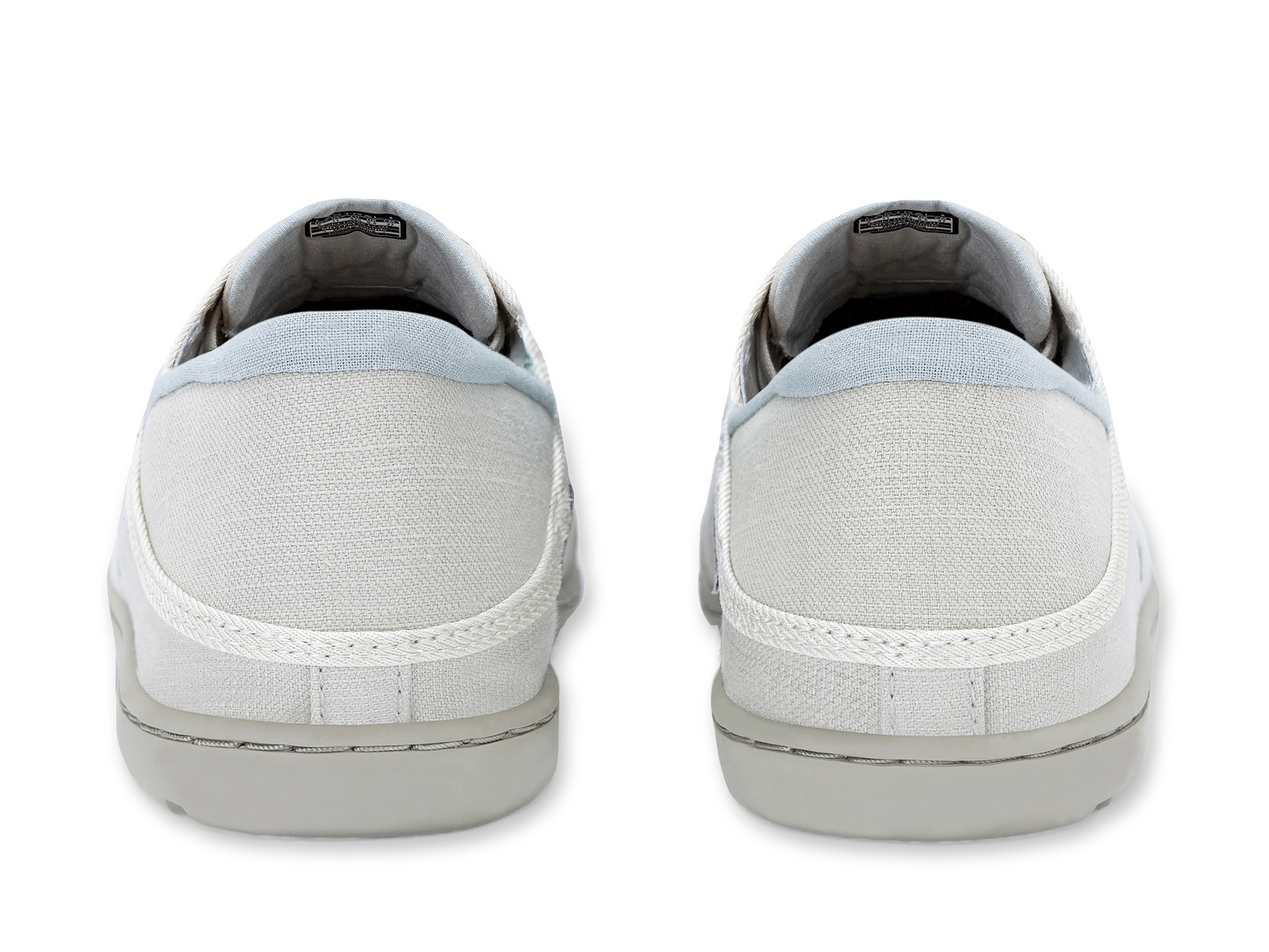Light colored canvas slip-on sneakers shown from heel view on white background