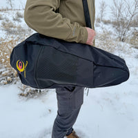 Navy snowshoe carry bag being held by person in snowy outdoor setting