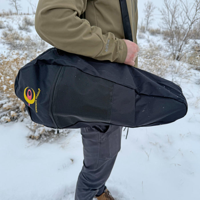 Navy snowshoe carry bag being held by person in snowy outdoor setting