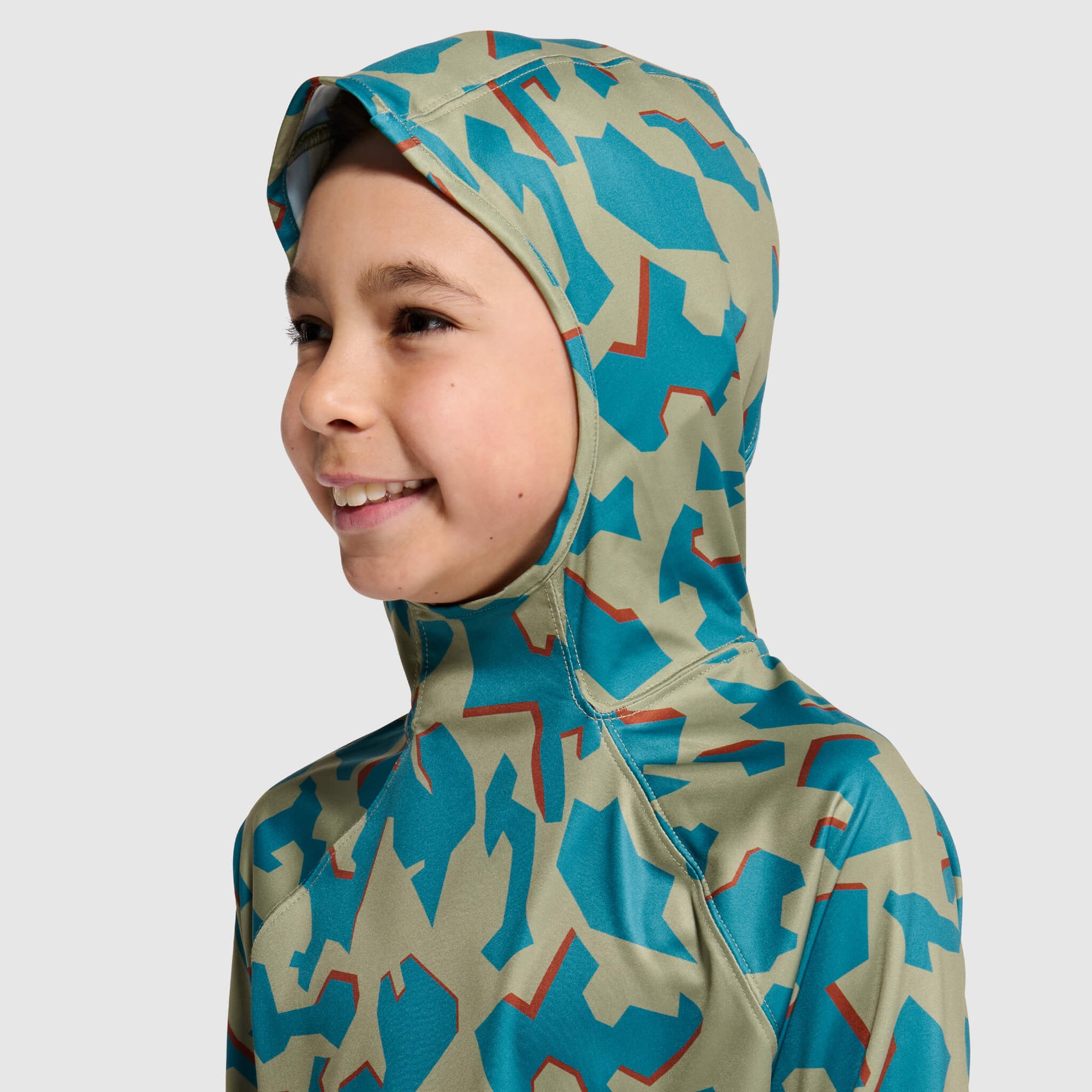Child wearing camouflage hooded top with sage green and teal pattern, side profile view