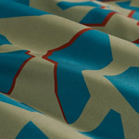 Close-up detail of camouflage patterned fabric with teal blue shapes on sage green base