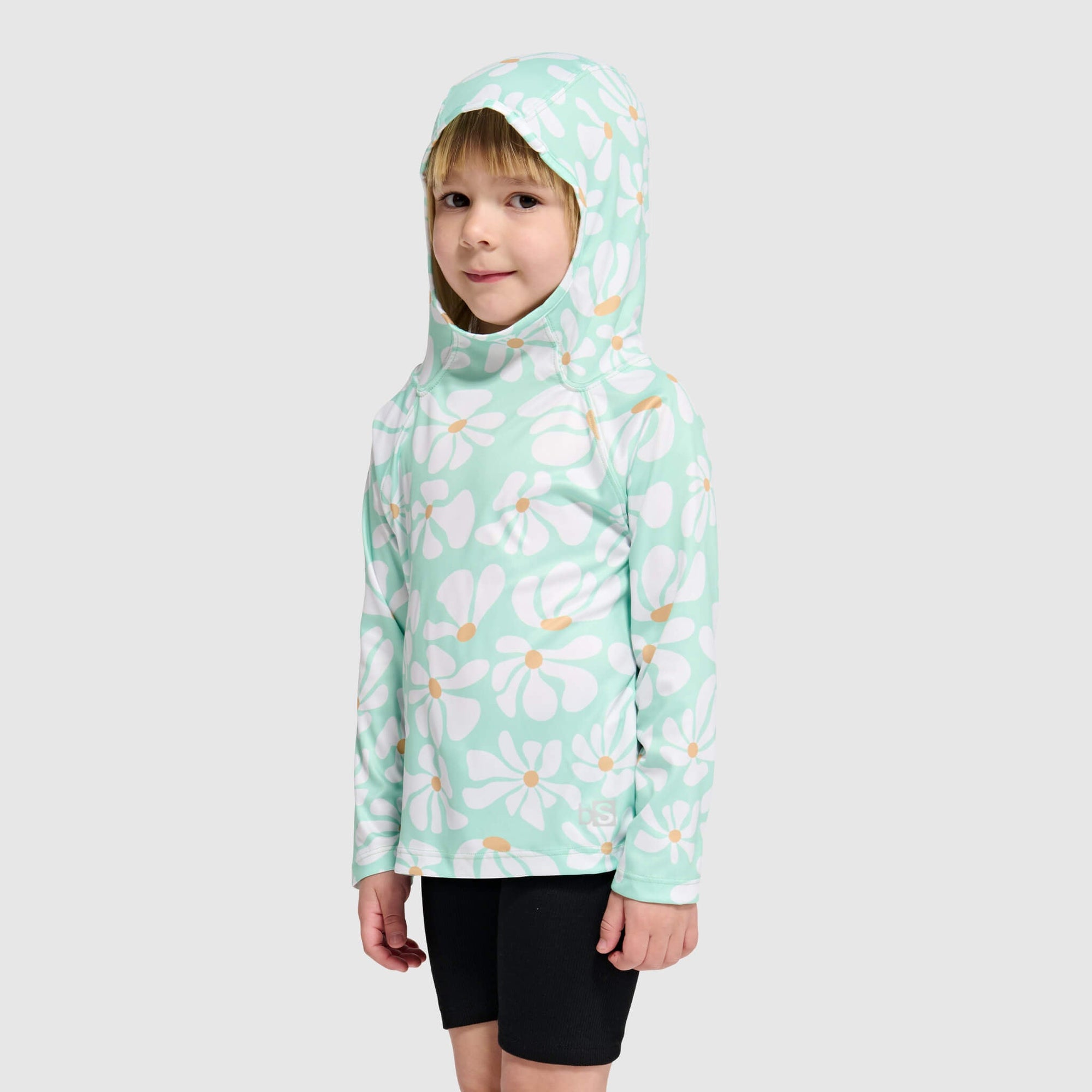 Child wearing mint green hoodie with white daisy pattern, hood up, front view
