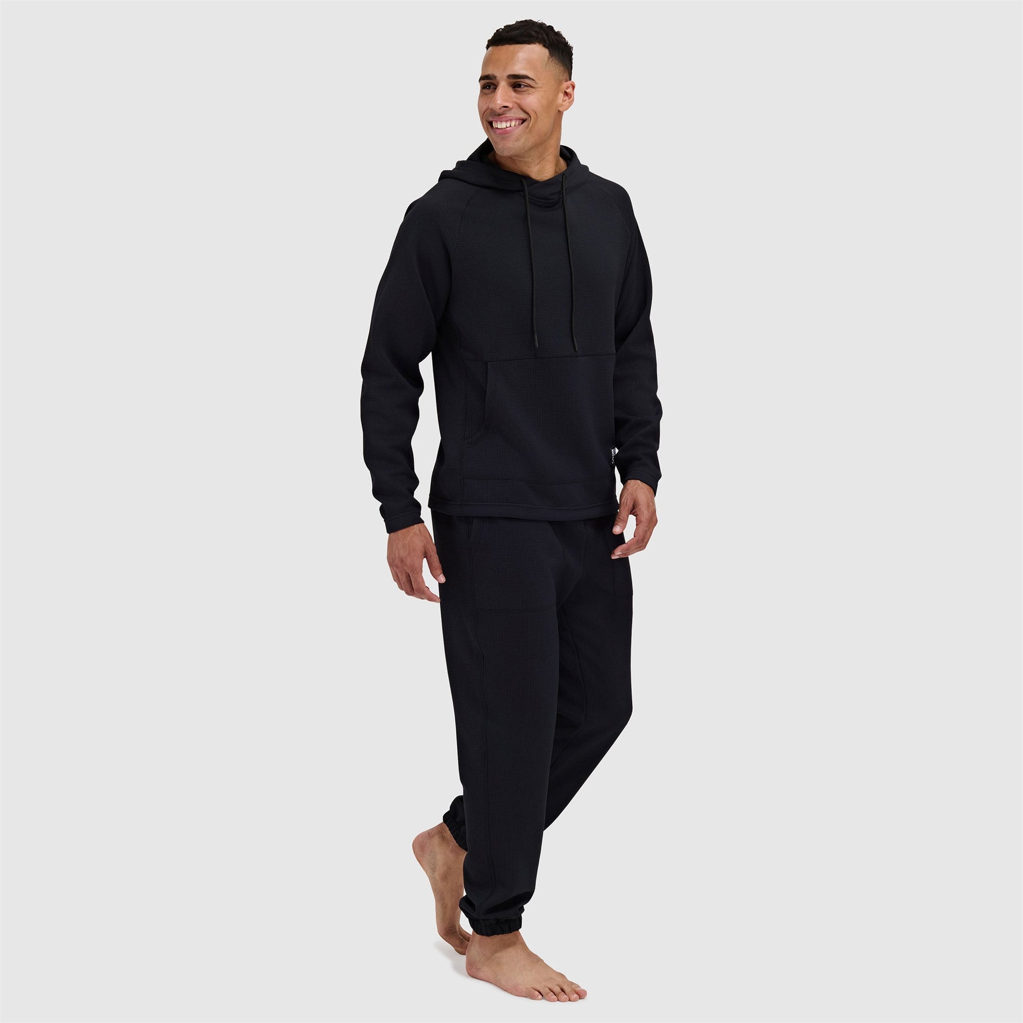 Black pullover hoodie with drawstrings and matching sweatpants on male model