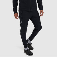 Men's slim-fit black jogger pants with zippered side pockets, worn with crocs, front angle view