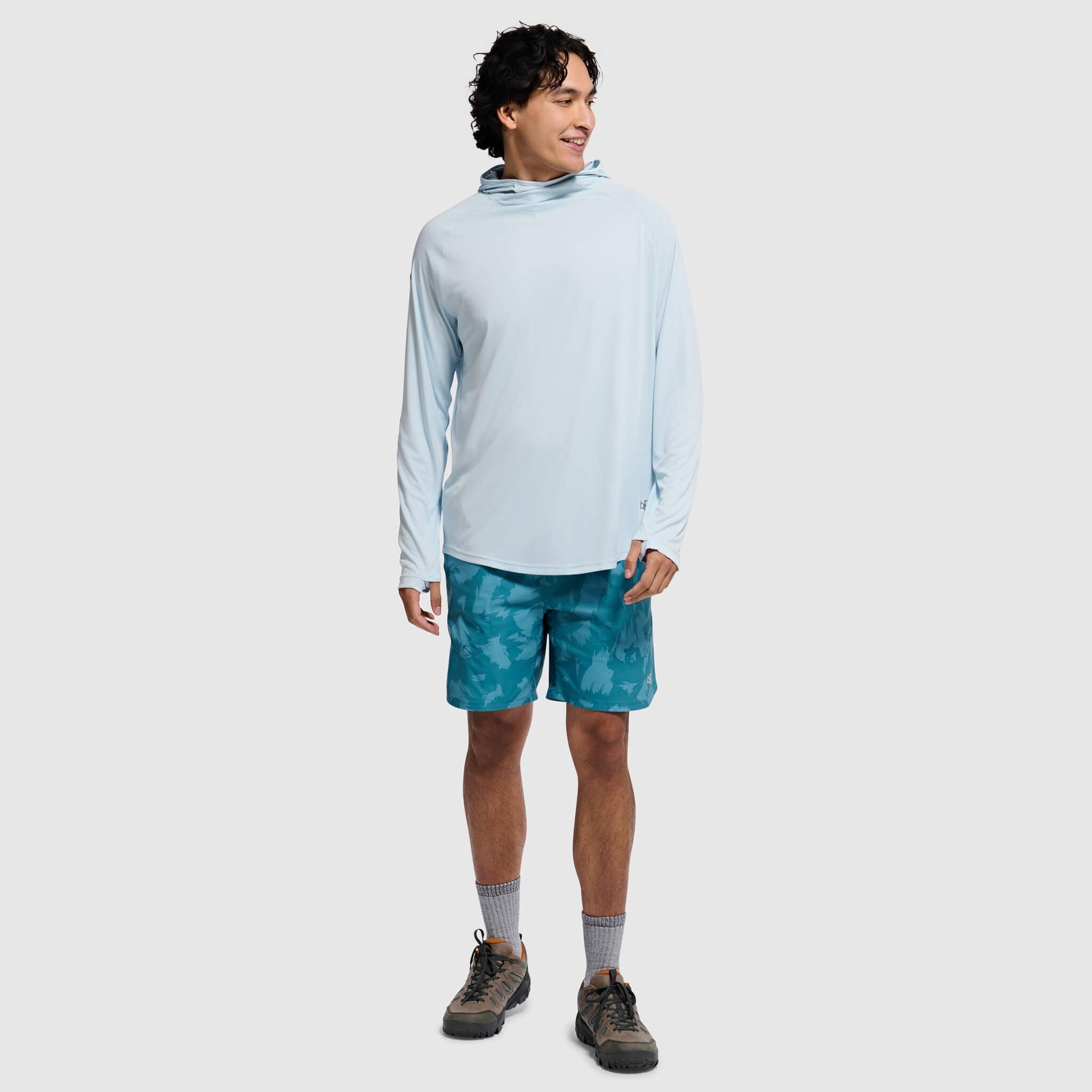 Light blue hooded long sleeve shirt with cowl neck, modeled by man in teal shorts