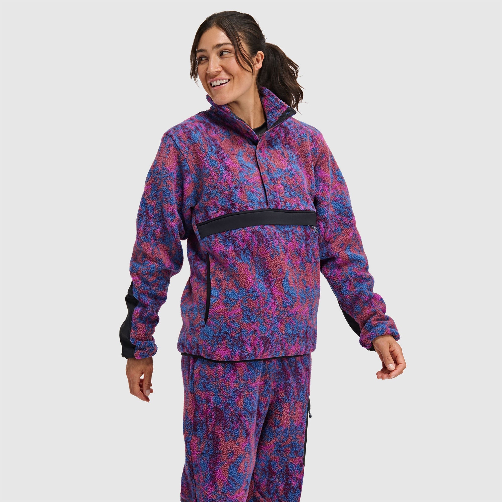Woman wearing purple and blue patterned fleece pullover with half-snap closure and black trim