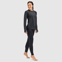 Women's long-sleeve crewneck base layer top with thumbholes, worn with matching leggings, front three-quarter view