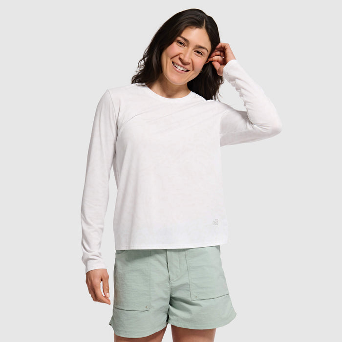 Woman wearing white long-sleeve crewneck sweatshirt with light green shorts, smiling pose