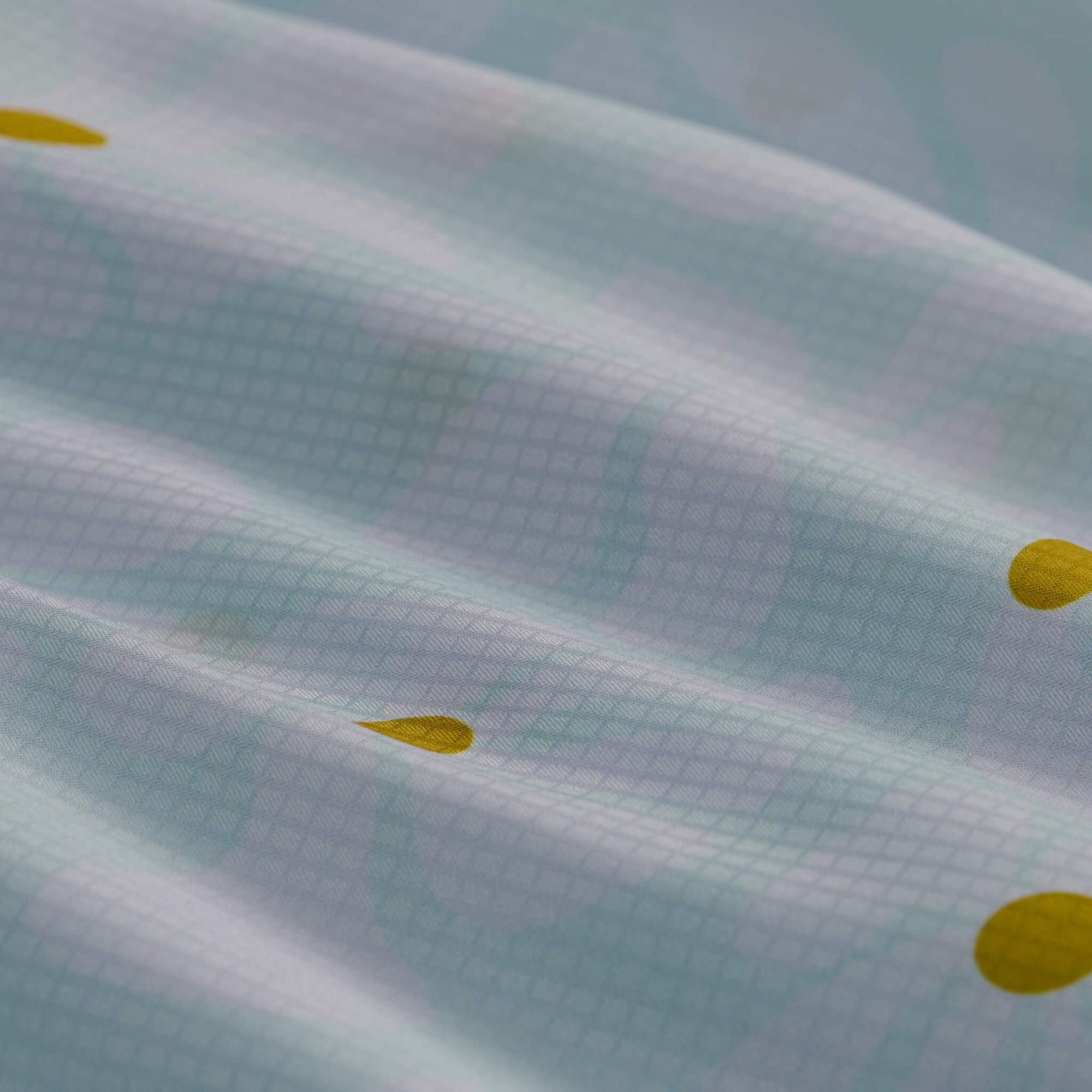 Light blue tie-dye camp shirt with yellow polka dots, close-up fabric detail view