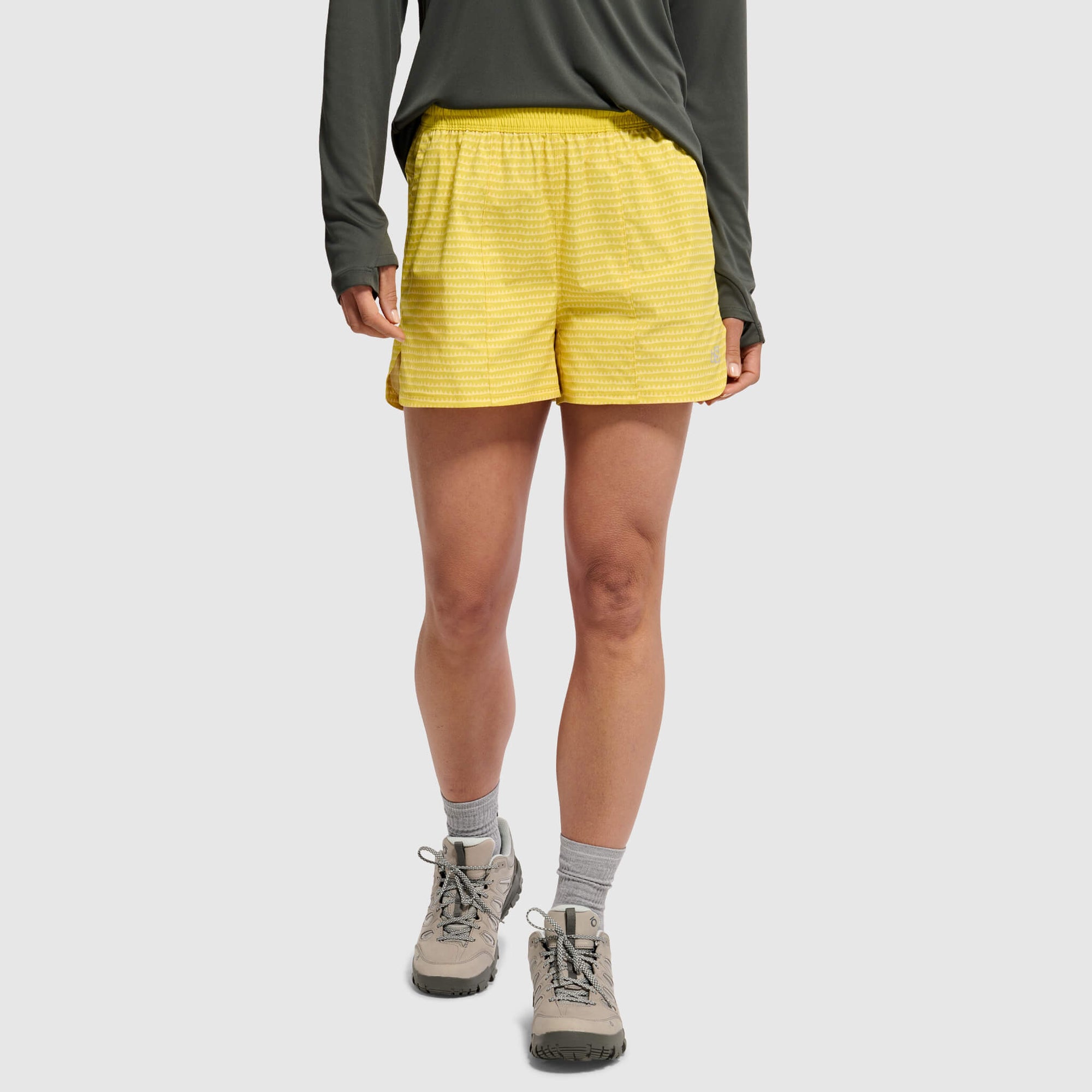Yellow athletic shorts with textured pattern worn with gray top and hiking boots