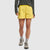 Yellow athletic shorts with textured pattern worn with gray top and hiking boots