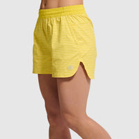 Yellow athletic shorts with dotted pattern and elastic waistband, side view on model