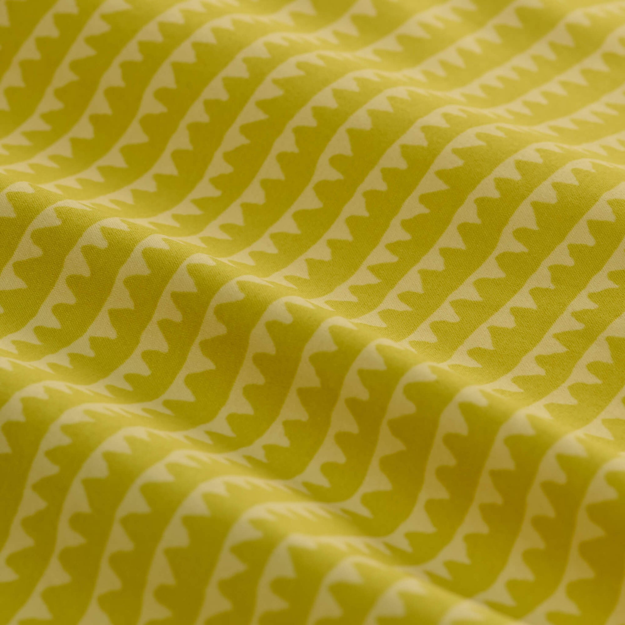 Yellow-green athletic shorts with geometric triangle pattern, draped fabric detail view