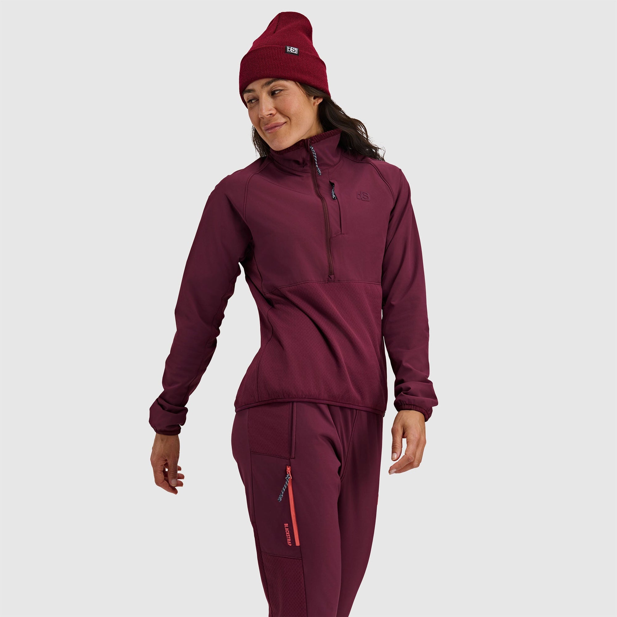 Woman wearing burgundy fleece half-zip pullover and matching pants with beanie