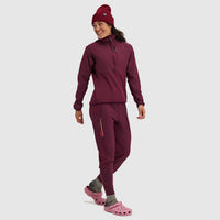 Woman wearing burgundy fleece half-zip pullover and matching pants with beanie