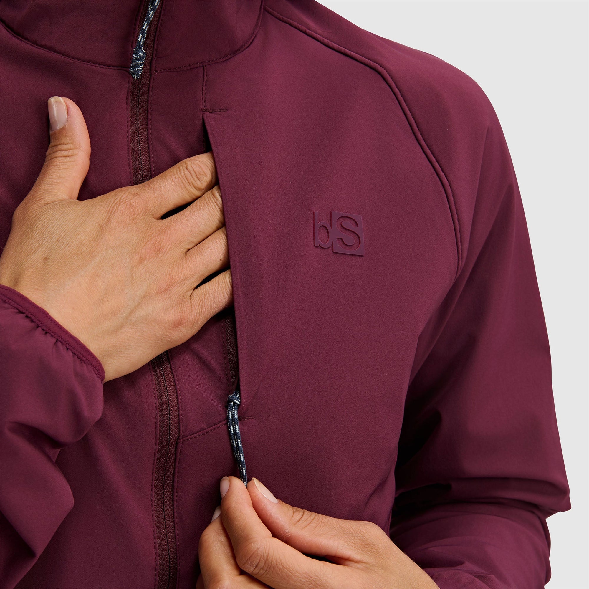 Burgundy half-zip fleece pullover jacket with embossed logo, worn by person adjusting zipper