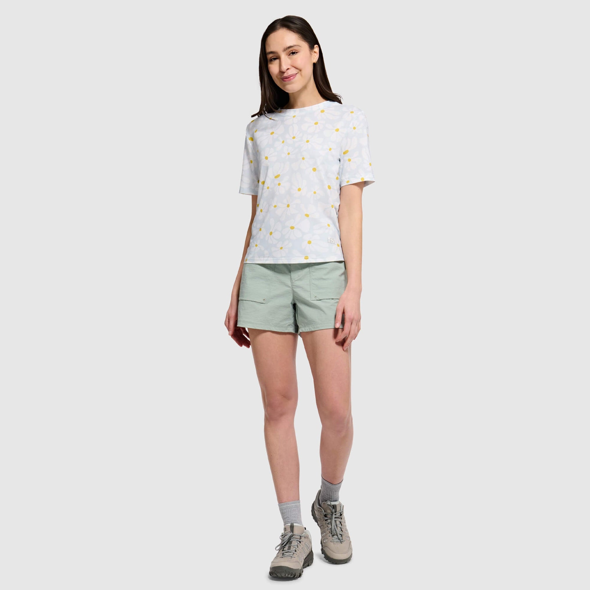 Woman wearing light gray polka dot t-shirt with green shorts in studio setting