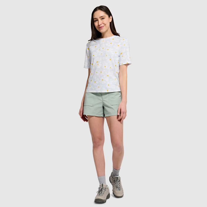 Woman wearing light gray polka dot t-shirt with green shorts in studio setting
