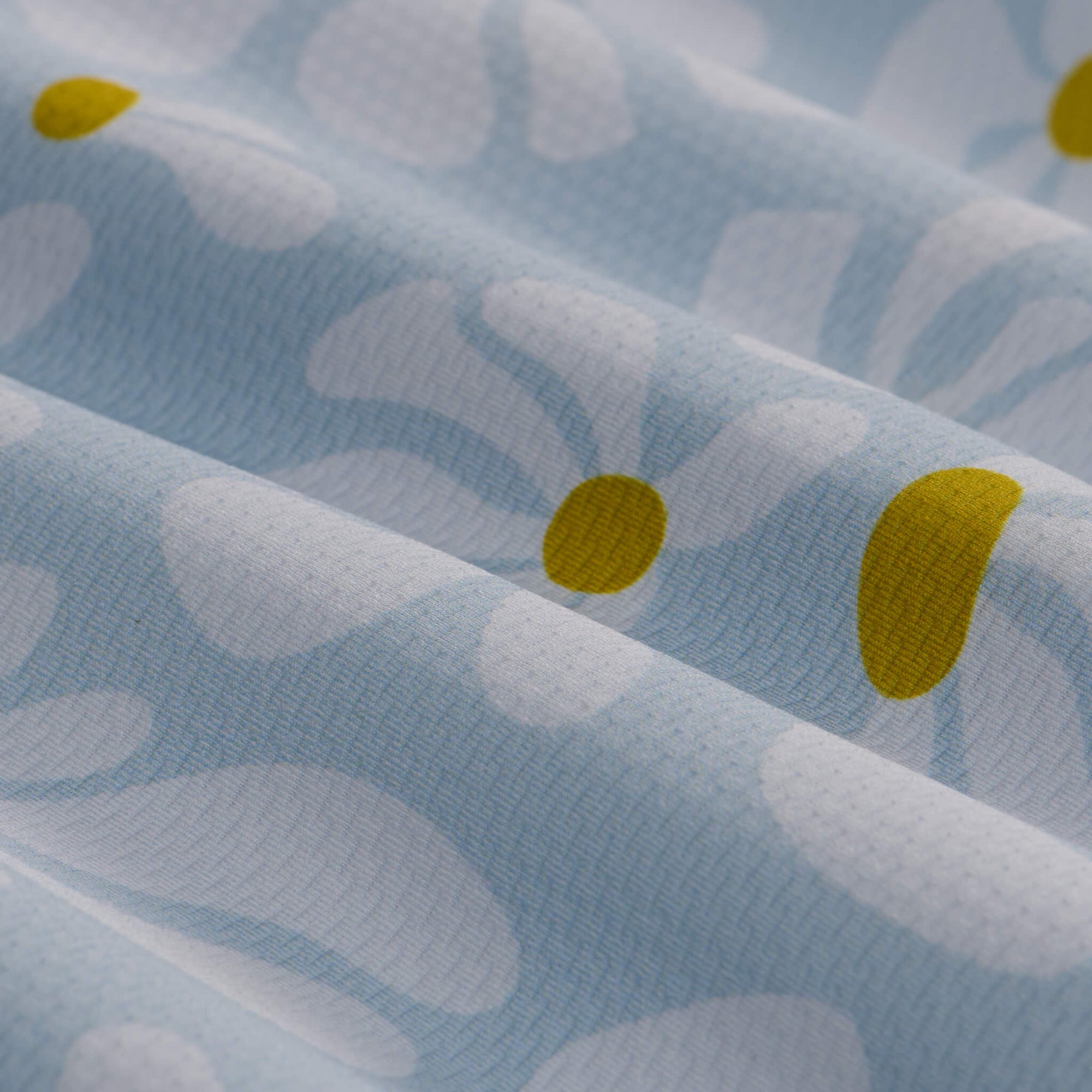 Light blue fabric with white daisy print and yellow flower centers in close-up detail