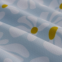 Light blue fabric with white daisy print and yellow flower centers in close-up detail