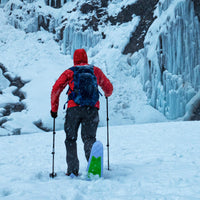 Person using black adjustable trekking poles while skiing through snowy winter landscape with ice formations