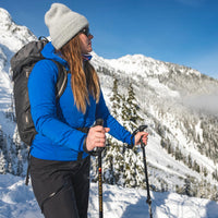 Woman holding black adjustable trekking poles in snowy mountain landscape