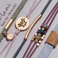 Collection of five hair tie bracelets with gold accents, beads, and varied cord textures on display card