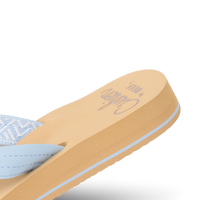 Women's flip-flop sandal with light blue straps and tan cushioned footbed, angled view