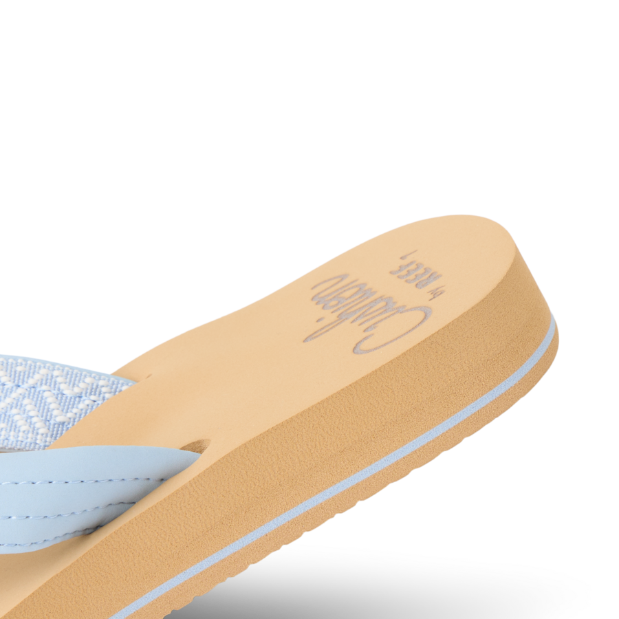 Women's flip-flop sandal with light blue straps and tan cushioned footbed, angled view