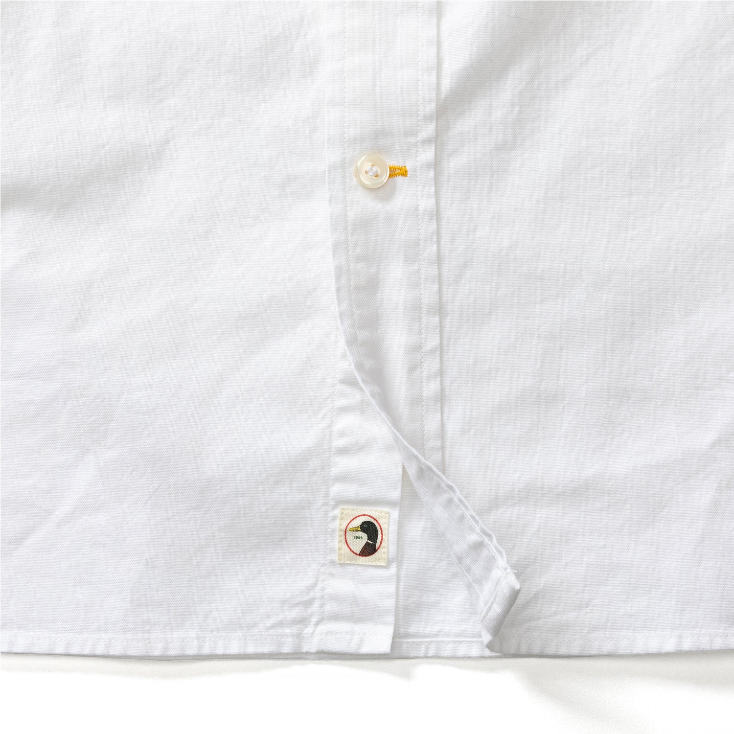White long sleeve oxford shirt detail showing button placket and brand label