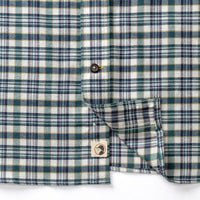 Close-up detail of plaid flannel shirt showing button placket, chest pocket, and brand logo tag