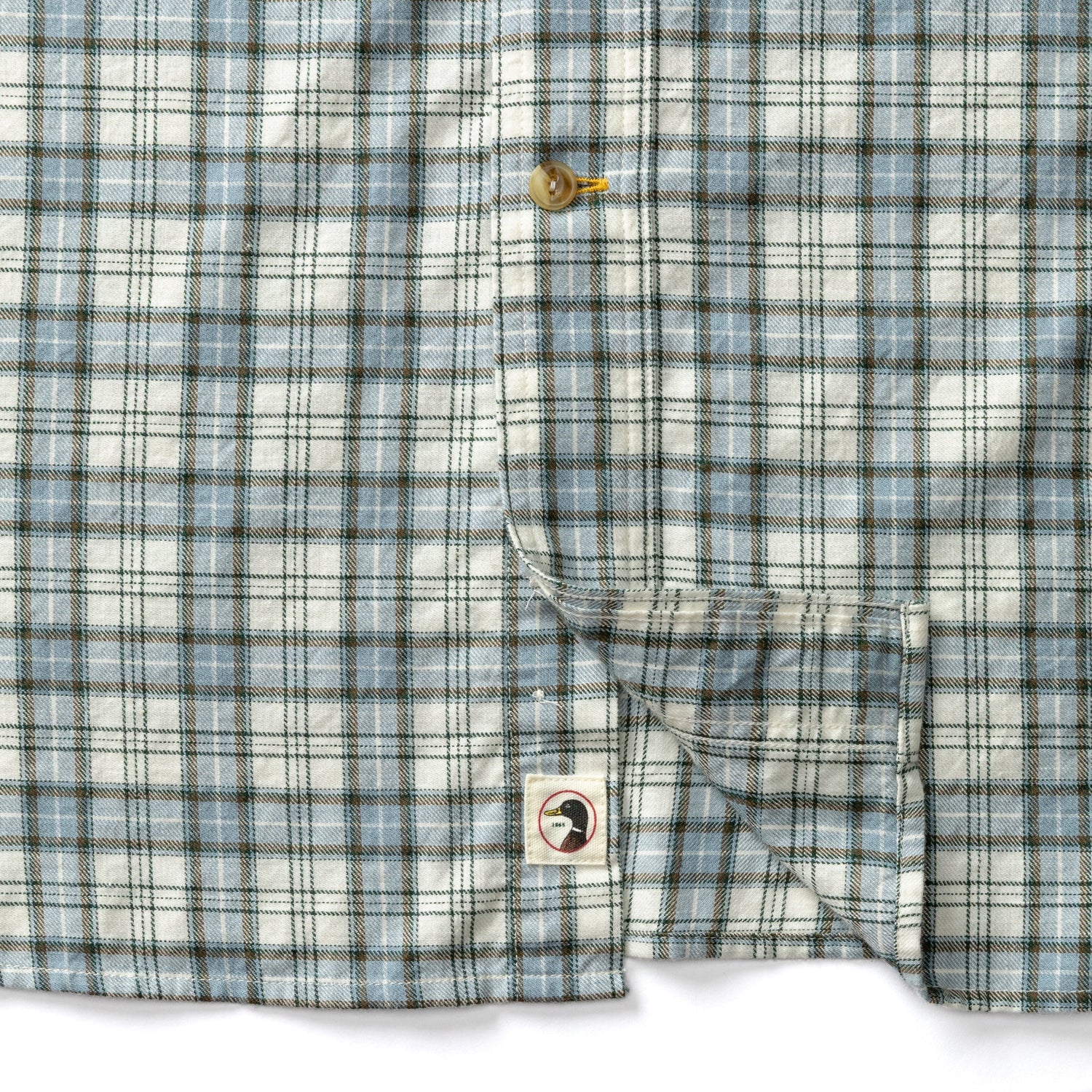 Close-up detail of plaid button-down shirt showing chest pocket and Duck Head logo patch