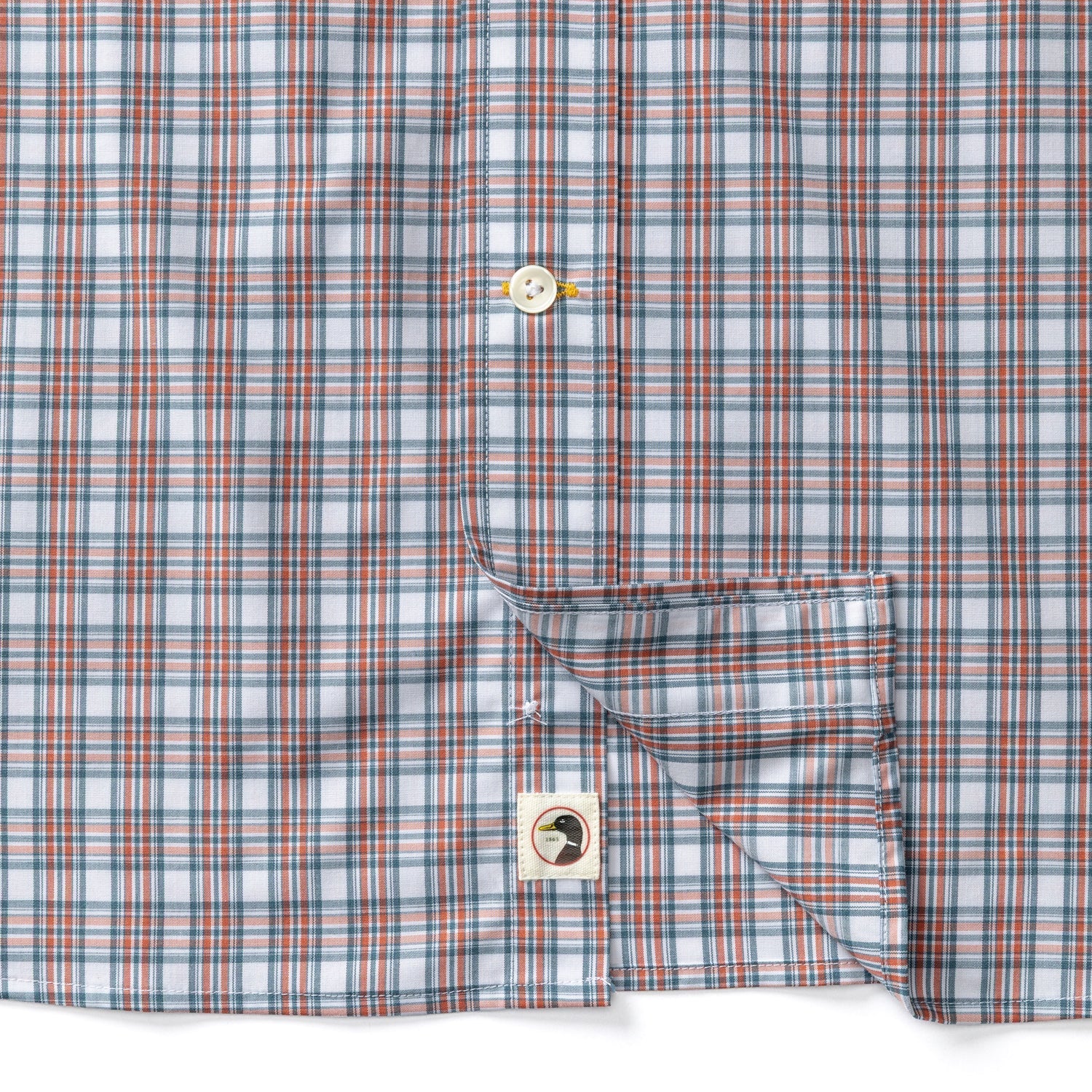 Close-up detail of plaid poplin shirt showing buttons, chest pocket, and duck logo patch