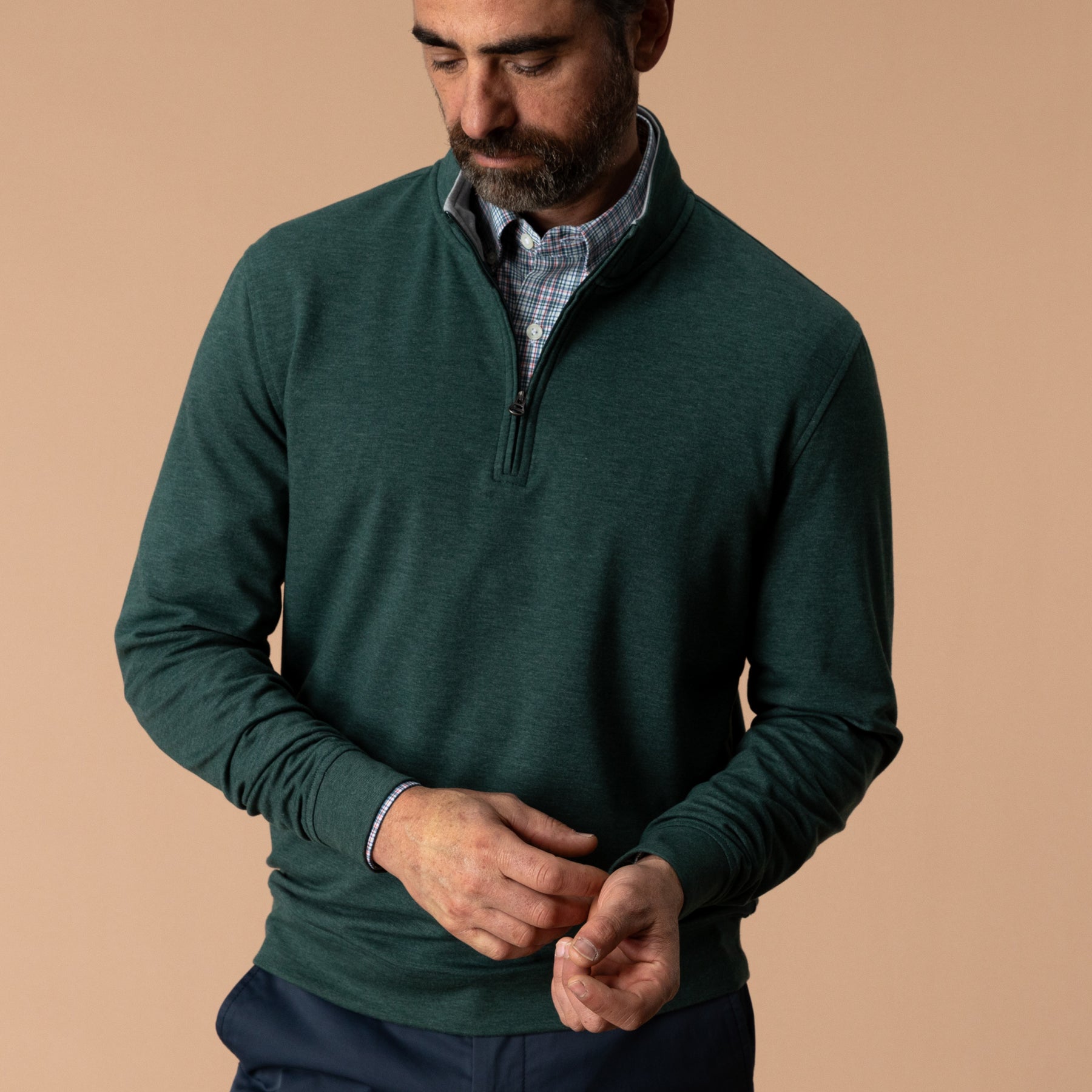 Men's dark green quarter-zip pullover layered over plaid shirt, front on-model view