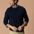 Men's navy crewneck sweater layered over plaid shirt, front three-quarter view
