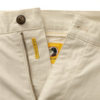 Light colored chino shorts with zipper fly and button closure, detail view showing waistband