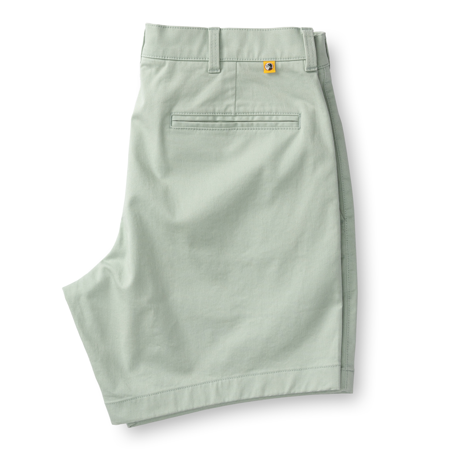 Light green chino shorts with welt pocket and orange logo tab, flat lay view
