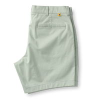 Light green chino shorts with welt pocket and orange logo tab, flat lay view