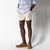 Light beige chino shorts worn with plaid shirt and brown loafers, studio shot