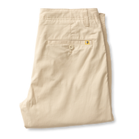 Beige chino pants folded showing back pocket with button detail and brand tab