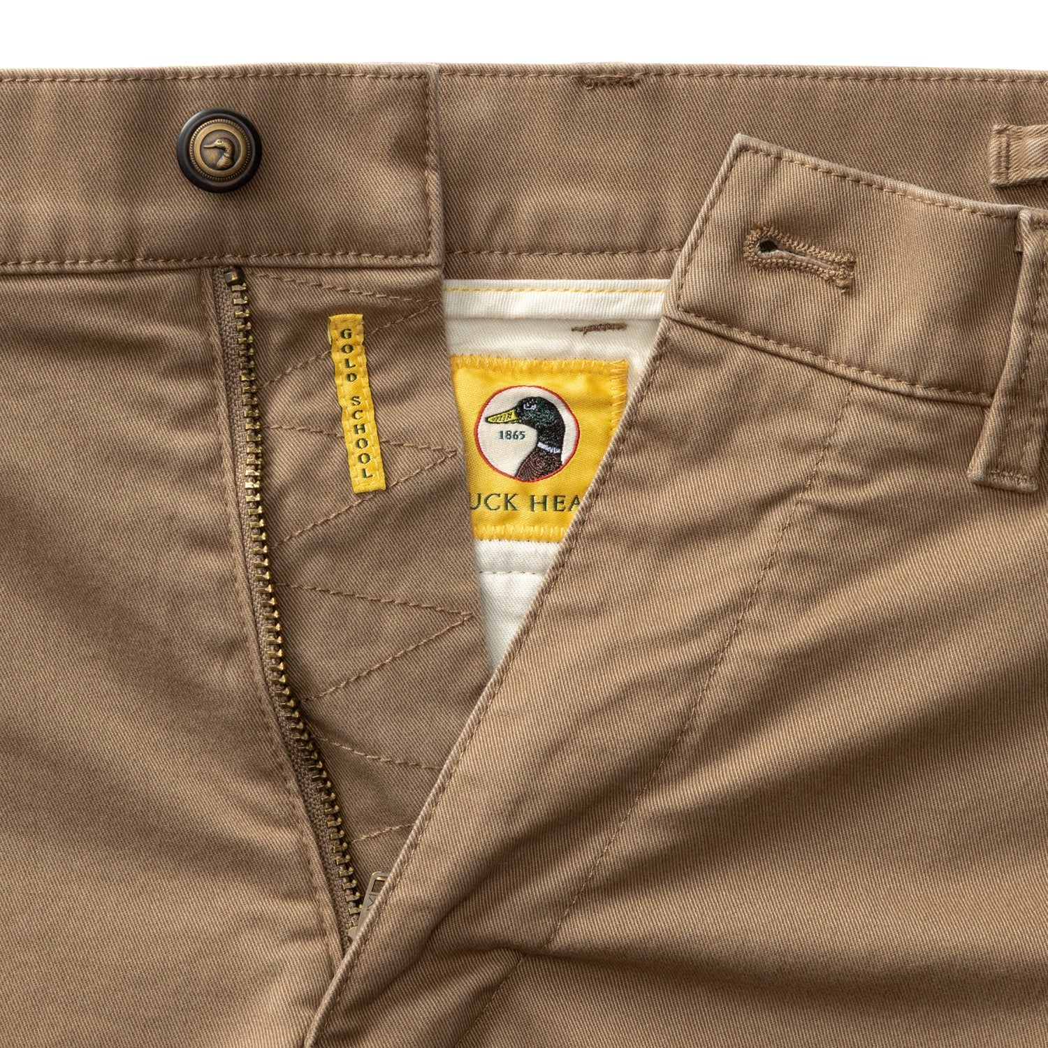 Close-up detail of chino waistband, zipper fly, and interior brand label with duck logo