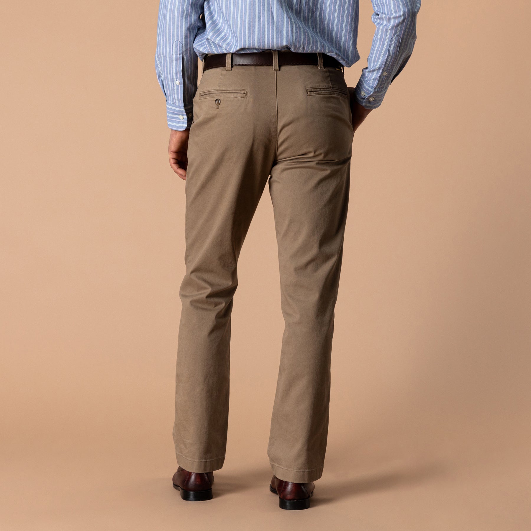 Men's classic fit chino pants in tan, back view, with belt and leather shoes