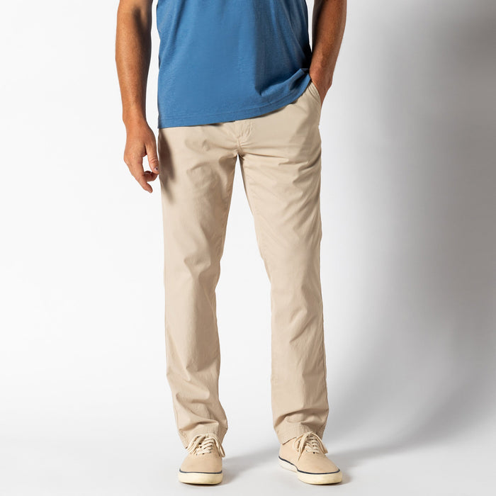 Light beige chino pants on male model with blue shirt, front view studio photo